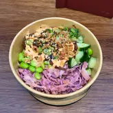 A straightforward, overhead shot of a beef brisket rice bowl served in a disposable takeaway container, likely taken at a food market.