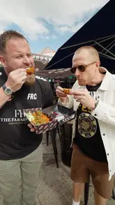 Two presenters discuss the upcoming Wing Fest event in Bristol while sampling chicken wings from a vendor called Gurt Wings. The video is a direct-to-camera conversation highlighting the event's features and the quality of the food.