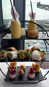 A montage showcasing an afternoon tea experience at Red Sky Bar, featuring a variety of savoury and sweet items, cocktails, and panoramic city views.