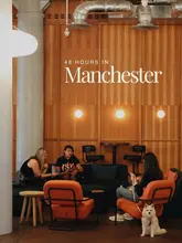 An atmospheric, well-composed shot of a modern hotel lounge or apartment lobby in Manchester, featuring comfortable seating and a dog, used as the cover image for a city guide.