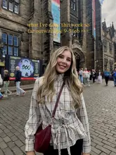 A lifestyle shot of a woman posing in front of a historic stone building, likely in Edinburgh or St Andrews, as part of a 'day in the life' style post.