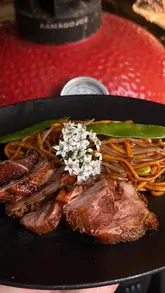 A first-person POV cooking video demonstrating how to marinate and sear duck breast on a Kamado Joe grill, served with a stir-fry.