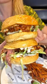 A short, punchy review of a visit to Byron Burgers, featuring close-ups of their loaded burgers, poutine fries, and desserts, alongside shots of the venue's interior.
