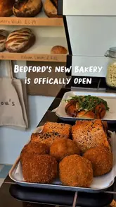 A short, punchy reel showcasing the offerings at a new bakery called Lou's Bakery in Bedford. The video features close-up shots of various baked goods including sourdough loaves, sausage rolls, toasties, and cookies, interspersed with brief glimpses of the shop's interior and exterior.