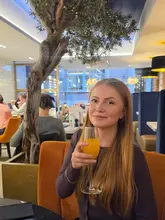 A portrait of a woman holding a Bellini in a restaurant setting, likely taken during a dinner visit.