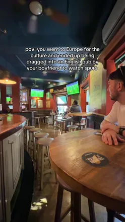 Couple joking about football at a cafe, showcasing a lighthearted moment in travel and sports culture.