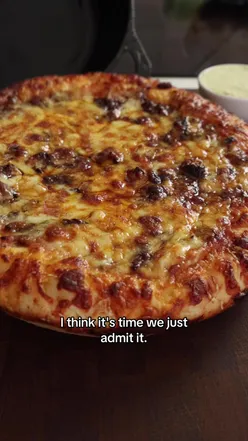 Delicious Birria Beef Pizza topped with melted cheese and fresh herbs, served on a rustic wooden table.