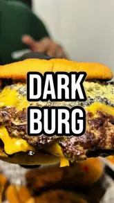 A high-energy food review vlog featuring a visit to a burger and chicken spot called 'DARK' in Park Royal, London. The creator samples several menu items, including a truffle burger, a Nashville sando, and a loaded tray, providing enthusiastic commentary on the flavours and quality.