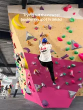A candid, eye-level shot of a person bouldering on a colourful climbing wall at The Climbing Hangar in Bristol, capturing the active environment of the gym.