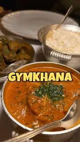 The video is a vlog-style review of Gymkhana, a Michelin-starred Indian restaurant in London. The creator provides a quick introduction before showcasing a variety of dishes, including cocktails, poppadoms, spicy prawns, tandoori broccoli, lamb chops, butter chicken, cumin potatoes, rice, naan, petit fours, and tiramisu. The video highlights the upscale dining experience and encourages viewers to watch the full review on YouTube.