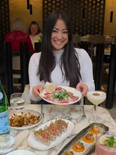 The video features a creator visiting Monmouth Kitchen in Covent Garden, showcasing a variety of small plates including tuna tacos, king prawns, and pizza, alongside cocktails and desserts. The review highlights the Peruvian-Italian fusion menu and the suitability of the venue for sharing dishes.