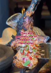 A promotional video for Tyga restaurant in Manchester, featuring a montage of the interior, menu, mocktails, and various dishes including lamb chops and rice. The video uses text overlays to highlight the dining experience.