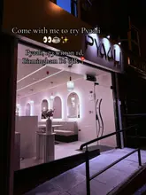 A clean, well-composed night shot of the exterior of a cafe called Pyaali in Birmingham. The image highlights the modern, minimalist interior design through the glass frontage, creating an inviting atmosphere.