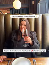 A portrait of a woman holding a glass of wine in a restaurant booth, with text overlays indicating a review of a steak restaurant.