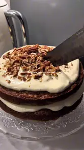 A short, visually appealing video demonstrating the slicing and serving of a homemade carrot cake, featuring close-up shots of the texture and cream cheese frosting.