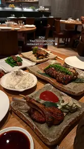 A POV-style shot taken from a seated position at a restaurant table, showcasing a spread of various Japanese dishes including skewers, ribs, and rice, intended to promote the venue for a date night.