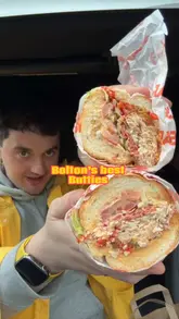 A group of friends travels to a sandwich shop in Bolton to review their subs. The video features the exterior and interior of the venue, followed by a taste test of three different sandwiches: buffalo chicken, philly cheese, and spicy italian.