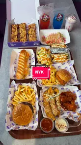 A promotional video showcasing a new menu at NYK Fried Chicken, featuring a variety of items including pizza, burgers, subs, wings, mocktails, and desserts. The creator presents the food in a casual, review-style format.