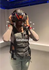 A vlog-style video showcasing a visit to Sandbox VR in Holborn, featuring a zombie-themed VR game and a robotic cocktail bartender.