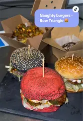 A short review video of Naughty Burgers in Bow, showcasing their unique coloured-bun burgers and loaded chips. The video includes shots of the venue exterior, interior, and close-ups of the food items.