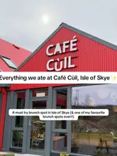 A clear, well-lit exterior shot of Café Cùil in the Isle of Skye, featuring a distinctive red building. The image includes text overlays identifying the venue and recommending it as a brunch spot.