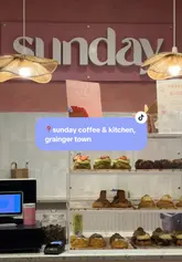 A short, aesthetic montage showcasing the interior and menu items of a pink-themed cafe in Newcastle, featuring matcha drinks and various baked goods.