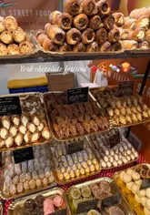 A quick-cut montage showcasing various food stalls at the York Chocolate Festival, featuring a wide range of sweet and savoury treats including chocolate-covered items, pizza, and brownies.