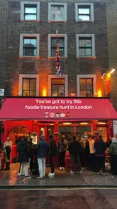 A couple participates in a food-based treasure hunt in London, following clues on their phones to navigate between different Asian street food locations. The video documents their journey through the city, solving riddles, and enjoying food and drinks along the way.