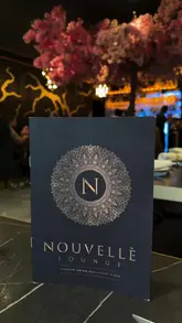A montage video showcasing the interior, cocktails, and Indian cuisine at Nouvellè Lounge. The video features slow, cinematic pans of the dining area, bar, and various dishes, including appetizers and curries served with dry ice for dramatic effect.