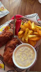 Dave's Hot Chicken meal: crispy spicy fried chicken tenders, crinkle-cut fries, and pickles served on a branded tray.