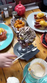 A vlog-style review of 'Hole in the Wall' in Crosby, Liverpool, highlighting their indulgent breakfast menu, including elaborate milkshakes and pancakes. The video provides a tour of the venue, showcasing the interior, the menu, and the dedicated kids' play area, positioning it as a family-friendly spot.