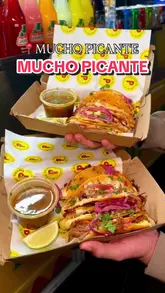 A short, energetic video showcasing birria tacos at Mucho Picante, featuring close-ups of the food being dipped in consommé and a shot of the venue exterior.