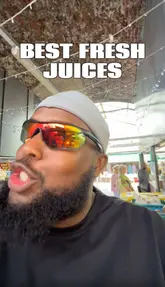 Two creators visit a juice stall in Shepherd's Bush Market to review their fresh, natural juices. They discuss the market's quality, the ingredients used in the drinks, and perform a taste test of various juices, including coconut and sugarcane blends.