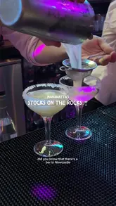 The video promotes the 'Stocks on the Rocks' event at Manahatta in Newcastle, where cocktail prices fluctuate based on demand, similar to a stock market. It features the creators visiting the bar, showing the digital menu board, the cocktail preparation, and their enjoyment of the drinks.