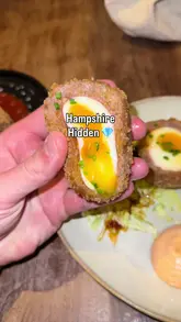 A food review video featuring two men visiting The Four Horseshoes in Nursling, Hampshire, showcasing a variety of dishes including a scotch egg, chicken supreme, slow-braised pork belly, smash burger, and various desserts.