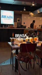 A promotional video for BRASA, a Brazilian BBQ restaurant located at Freight Island in Manchester. The video features close-up shots of the churrasco cooking process, including open flames, and showcases various dishes such as flatbreads, croquettes, and steak, highlighting the family-style sharing concept.