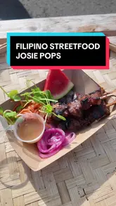 The creator visits Josie Pops Kitchen at Barras Market to review their Filipino street food offerings. She tries the lumpia, pork skewers, pork rice bowl, and ube cake, providing commentary on the taste and texture of each dish.