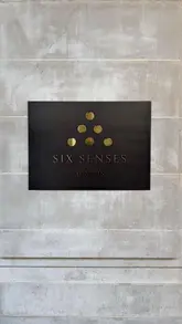A clean, centered, high-quality photograph of the Six Senses London signage mounted on a stone wall.