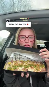A video review of a takeaway meal from Steak Fuel in Bolton, filmed by a creator inside their car. The creator discusses the portion size, the sauce, and the quality of the ribeye steak and chips, while also including a brief appearance by another person to share their opinion.