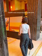 A photo of a person walking through the Temple of Peace in Cardiff, viewing a contemporary art exhibition. The image captures the grand architecture of the venue alongside the art display.
