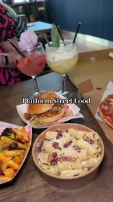 The creator visits 'Platform Street Food' in Cardiff Bay, providing a tour of the venue, demonstrating the QR code ordering system, and reviewing dishes from several different vendors including burgers, pizza, pasta, and ice cream.