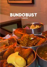 A fast-paced, music-synced montage showcasing a variety of Indian street food dishes and drinks at Bundobust in Leeds. The video features close-up shots of the food, including bhajis, potatoes, and lassis, alongside a brief exterior shot of the venue.