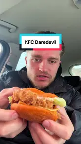 A creator reviews the limited-edition 'Daredevil' menu from KFC, specifically testing the loaded fries, chicken burger, and hot wings while sitting in a car. The video features direct-to-camera commentary and close-up shots of the food items.