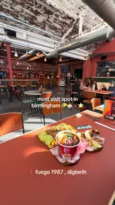 A short, energetic video featuring a creator introducing a street food spot called Fuego 1987 located in a food hall in Digbeth, Birmingham. The video highlights various dishes including loaded fries and birria tacos, showcasing the food's appeal with close-up shots.