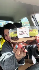 The video features a creator visiting a self-service cake shed in Swansea. The content focuses on the ASMR experience of opening the shed, selecting various desserts like cheesecake, brownies, and milkshakes, and then taste-testing them in a car.