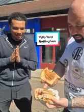 A creator reviews a Caribbean/Jamaican street food spot called Yello Yard in Nottingham. He samples a jerk pork sandwich, discusses the sauce, and interviews the owner who shows a large pot of the marinade.