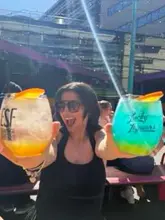 A creator visits Edinburgh Street Food on a sunny day, showcasing the outdoor seating area, various cocktails, and a meal of chicken tenders and waffle fries.