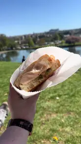 A short, energetic reel showcasing a visit to Mootz in Stockbridge, Edinburgh. The video features a handheld shot of a sandwich being enjoyed in a nearby park, followed by a quick tour of the venue's interior, including the menu board, decor, and a polaroid wall.