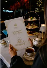 A montage video showcasing the 'Silk Route' afternoon tea at Coco Grill & Lounge in London. The video features high-quality, slow-motion shots of the venue's interior, the tea service, various sweet and savoury items, and the view of Tower Bridge.