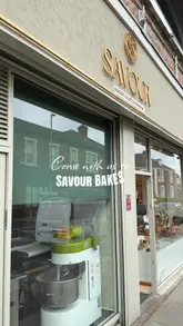 A montage video showcasing the interior and product displays of Savour Bakery, featuring a wide variety of pastries, sandwiches, and breads.